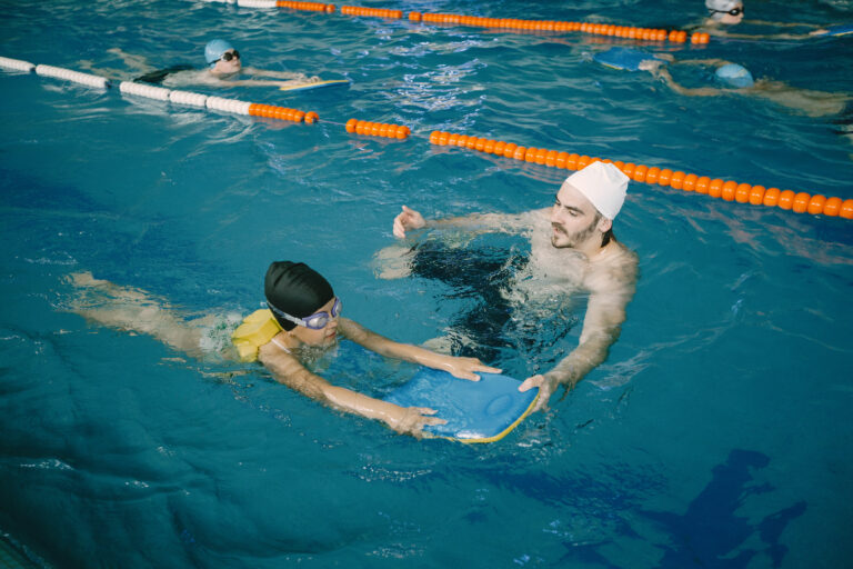 Girl learning to swim with coach at the leisure center